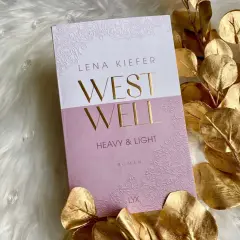 Lena Kiefer Roman "Westwell" auf flauschigem Untergrund, umrahmt von goldenen Blättern.