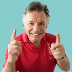 Steffen Barth zeigt mit beiden Zeigefingern nach oben und lächelt. Er trägt ein rotes Poloshirt mit dem Aufdruck "SANOTAPE".