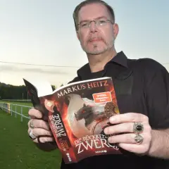 Mann hält Buch "Die Rückkehr der Zwerge" von Markus Heitz. Die Zwerge reihenfolge ist hier wichtig für die Geschichte.