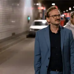 Ein Mann im blauen Anzug, vielleicht ein Ermittler wie Danowski, steht im Tunnel. Im Hintergrund arbeiten Personen in Schutzanzügen.