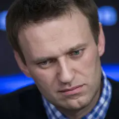 Alexei Nawalny, mit ernstem Blick und blau kariertem Hemd, im Scheinwerferlicht.