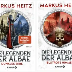Zwei Buchcover von Markus Heitz: "Die Legenden der Albae - Dunkles Erbe" mit einem Elfen vor einer düsteren Stadt und "Die Legenden der Albae - Blutrote Himmel" mit einem Totenkopf vor einer apokalyptischen Landschaft.
