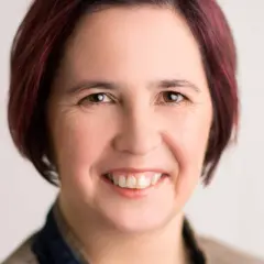 Nicole Peters lächelt freundlich in die Kamera. Ihr kurz geschnittenes, dunkelrotes Haar umrahmt ihr Gesicht.