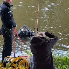 Polizei-Taucher sucht nach Beweisen. Ein Polizist sichert die Leine, während eine Frau die Tiefe misst. Ein Fall von mord auf hoher see?