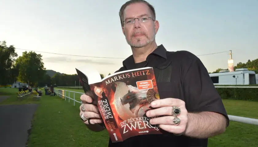 Mann hält Buch "Die Rückkehr der Zwerge" von Markus Heitz. Die Zwerge reihenfolge ist hier wichtig für die Geschichte.