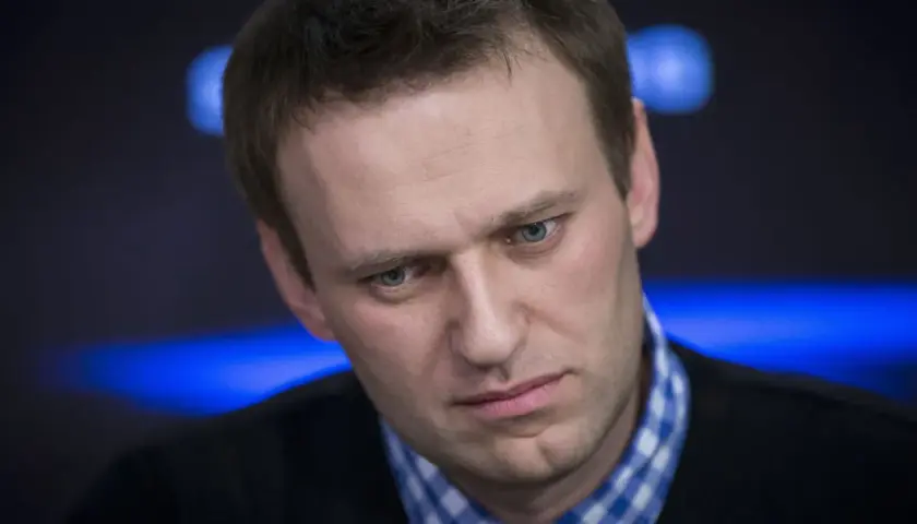 Alexei Nawalny, mit ernstem Blick und blau kariertem Hemd, im Scheinwerferlicht.