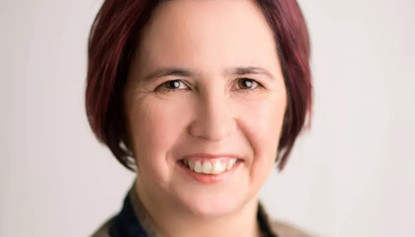 Nicole Peters lächelt freundlich in die Kamera. Ihr kurz geschnittenes, dunkelrotes Haar umrahmt ihr Gesicht.