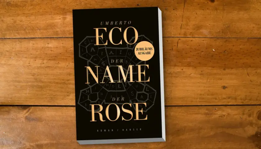 Umberto Ecos Roman "Im Namen der Rose" als Jubiläumsausgabe auf Holztisch.