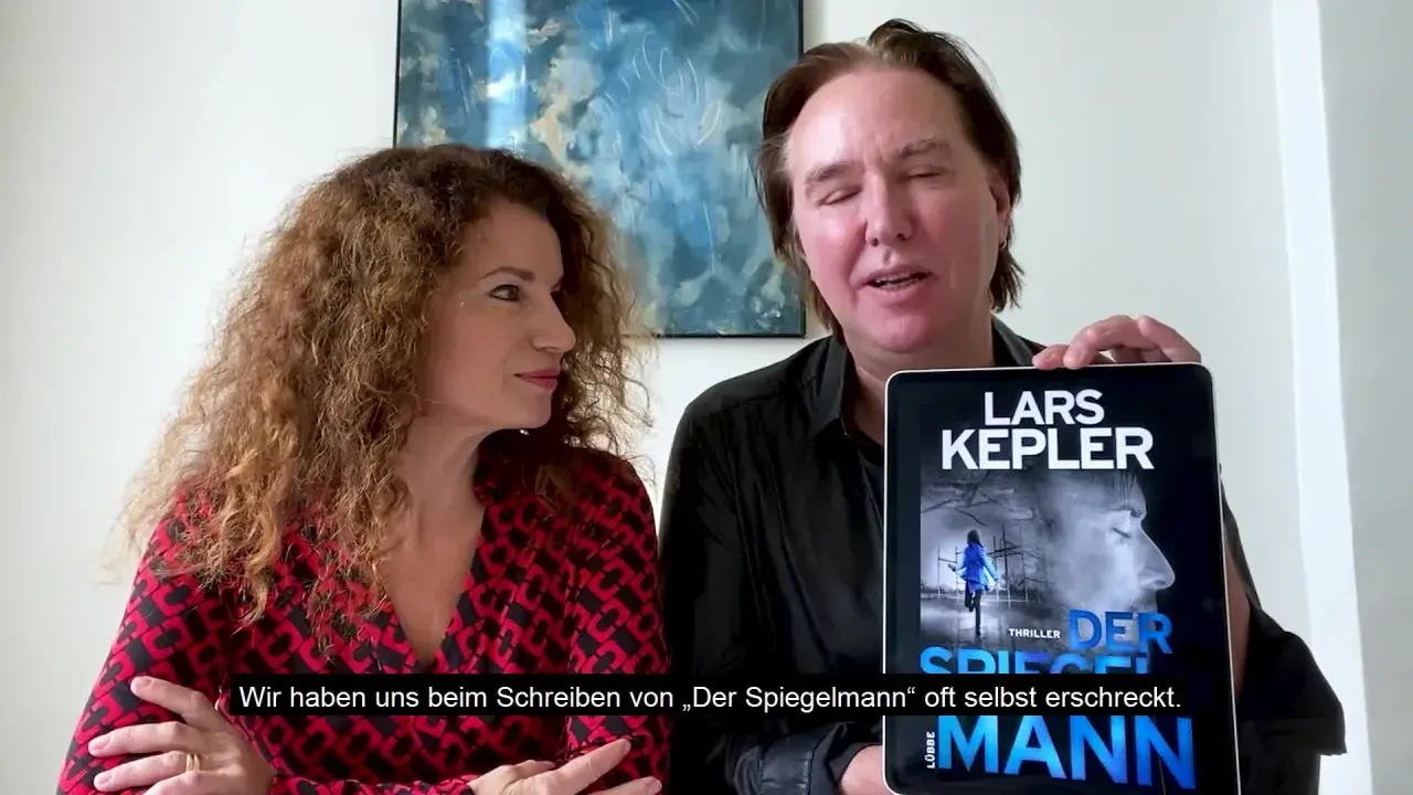 Ein Mann und eine Frau präsentieren ein Tablet mit dem Cover von "Der Spiegelmann" von Lars Kepler.