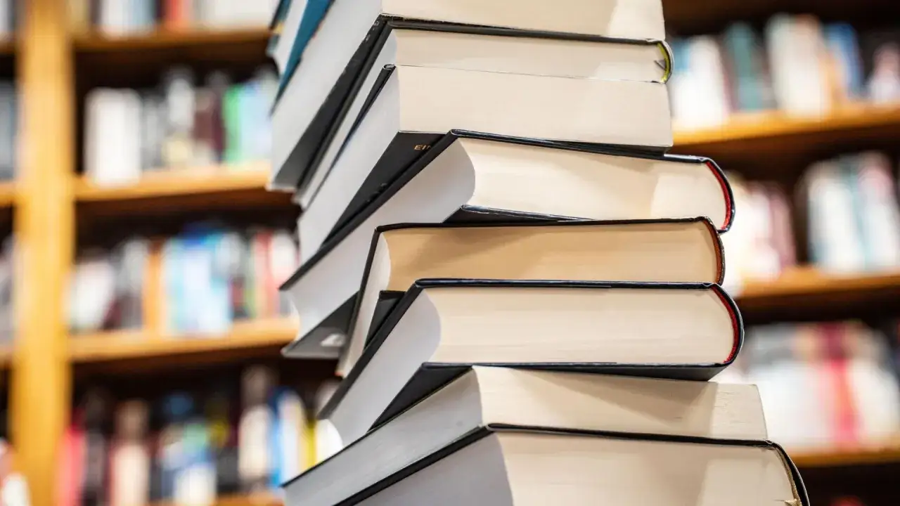 Stapel von Büchern, die wie ein Sunday Times Bestseller aussehen, stehen vor einem unscharfen Bücherregal.