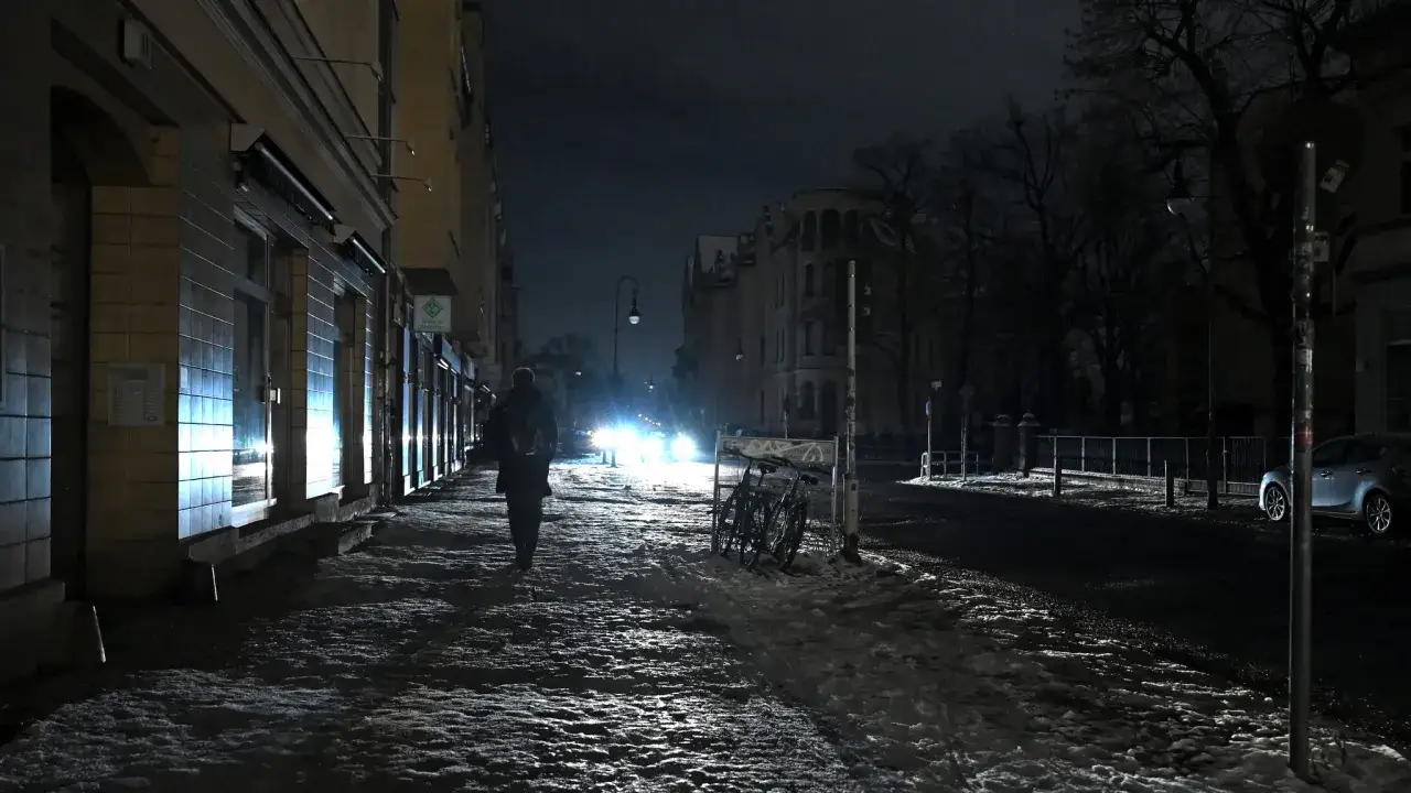 Ein Mann geht nachts durch eine verschneite Berliner Stra&szlig;e. Autoscheinwerfer blenden, Fahrr&auml;der stehen am Wegesrand. Er wirkt wie der Pate von Berlin.