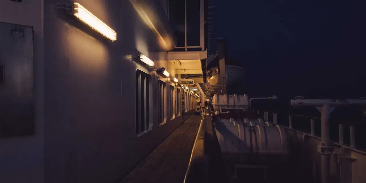 Dunkler Gang auf einem Schiff bei Nacht. Die Neonlichter werfen lange Schatten. Ein Gef&uuml;hl von Einsamkeit und Geheimnis, fast wie ein Tatort: Mord auf hoher See.